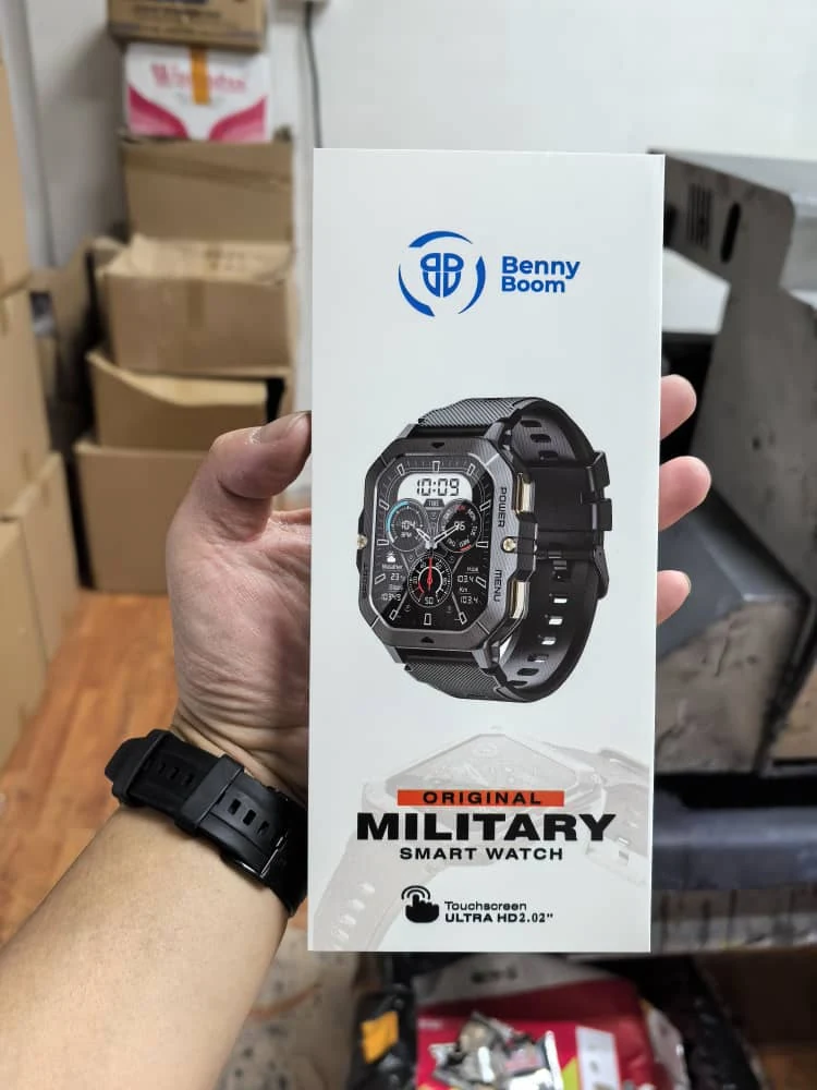 The BennyBoom Military Smart Watch shown at an angle, face lit, showing heart rate, steps, weather and calories on the display
